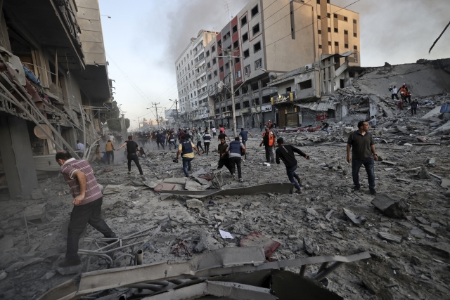 Rescuers and people gather amidst the rubble in front of Al-Sharouk tower that collapses after being hit by an Israeli air strike, in Gaza City, on May 12, 2021. An Israeli air strike destroyed a multi-storey building in Gaza City today, AFP reporters said, as the Jewish state continued its heavy bombardment of the Palestinian enclave.© Mohammed Abed / AFP